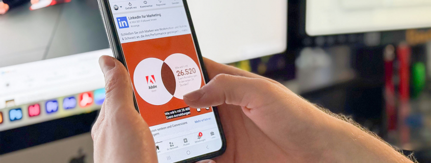 Person hält ein Smartphone in den Händen, auf dem die LinkedIn App zu sehen ist